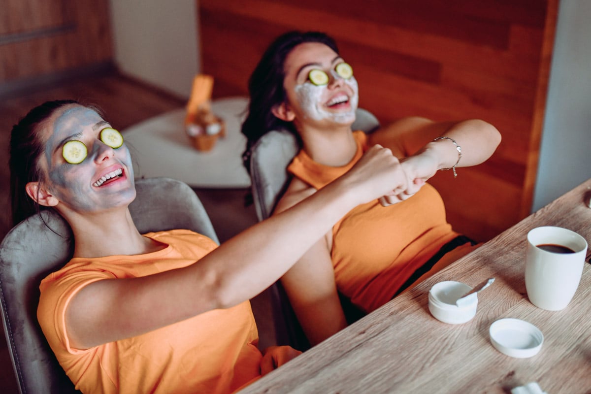 Deux filles se bousculent alors qu'elles se détendent avec un masque facial bricolage sur leur visage.