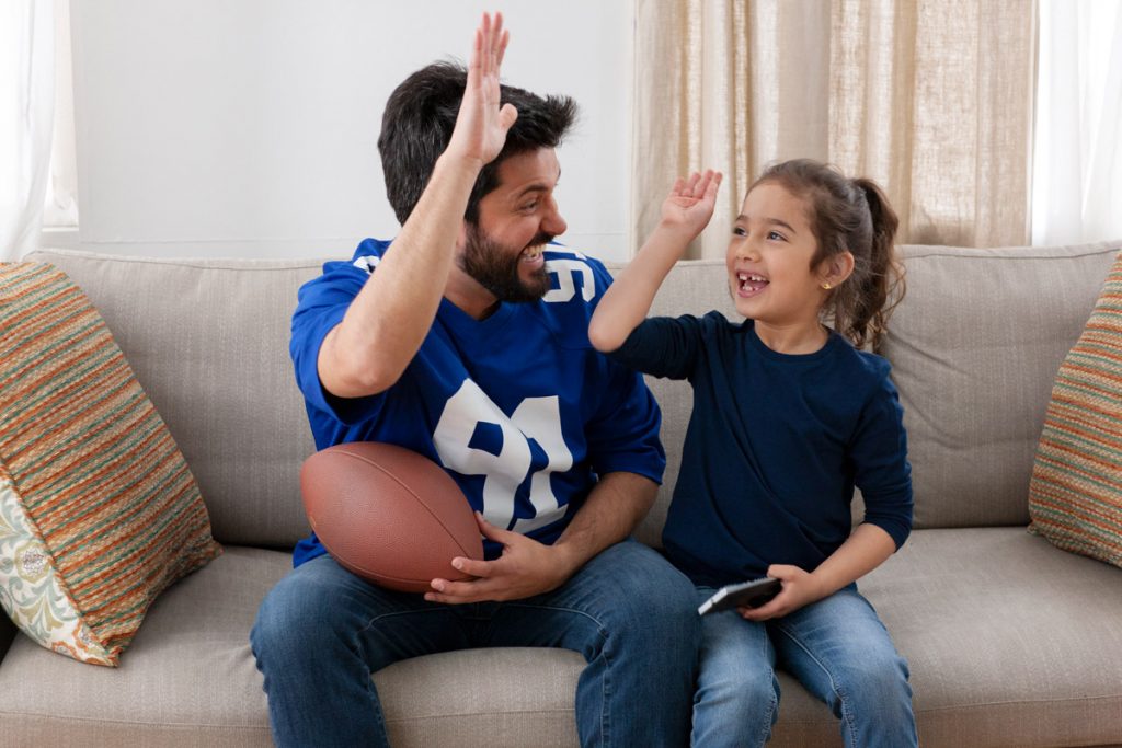 Un père et une fille se sont élevés les uns les autres tout en regardant un match de football à la télévision.