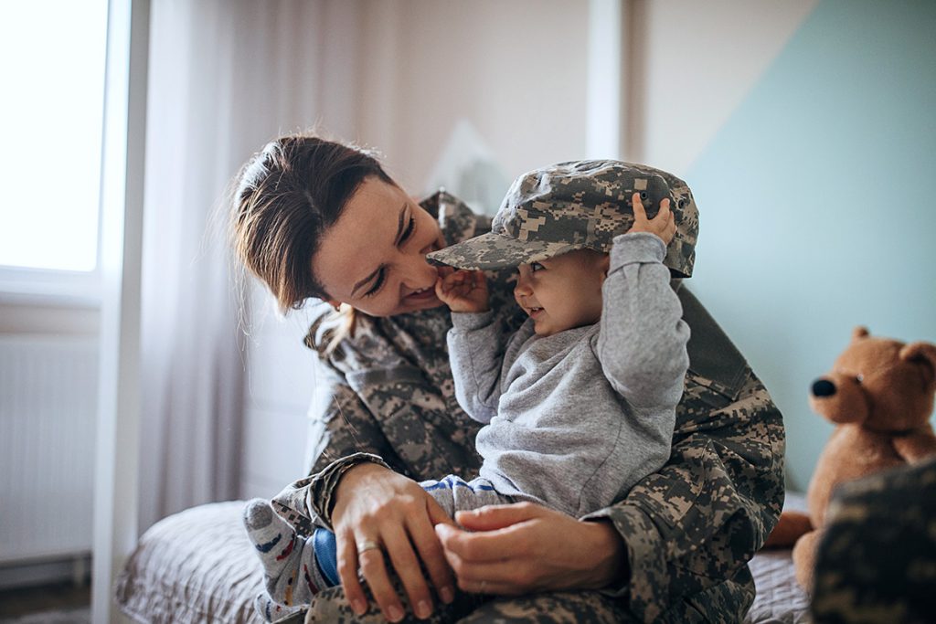 Une photo de stock représente une maman militaire étreignant son enfant.