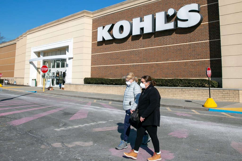 Les gens passent devant un grand magasin de Kohl tout en portant des vestes et des masques faciaux.