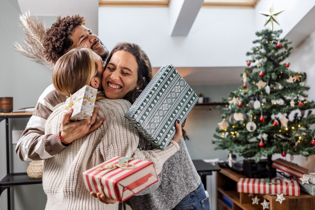 Trois amis s'embrassent en échangeant des cadeaux de Noël.