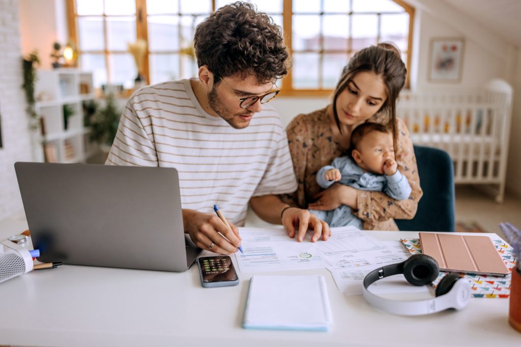 Jeune famille avec un petit petit garçon mignon qui passe en revue les finances à la maison