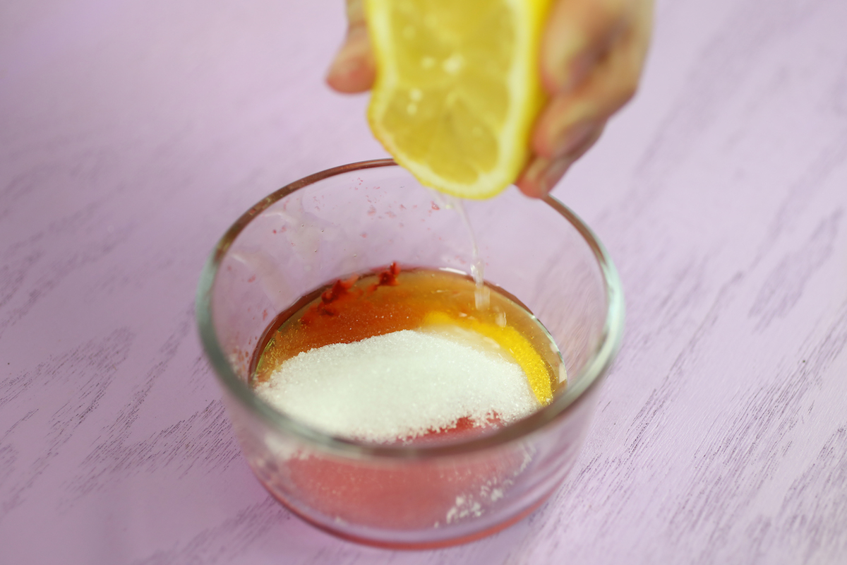 Le jus de citron étant serré dans un bol avec des ingrédients pour le gommage à lèvres