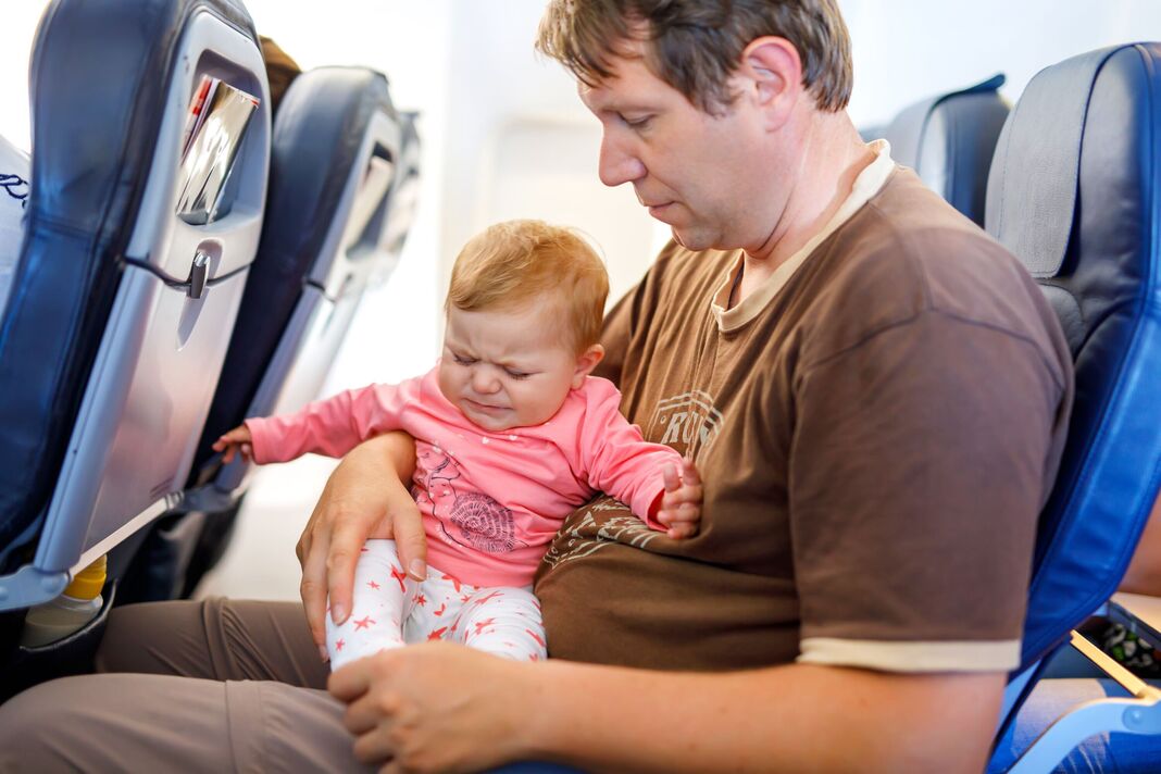 Jeune père triste fatigué et sa petite fille qui pleure pendant le vol en avion en vacances. Papa tenant une petite fille sur le bras. Voyage en avion avec bébé, Jeune père triste fatigué et sa petite fille qui pleure pendant le vol en avion en vacances. Papa tenant une petite fille sur le bras. Voyage en avion avec bébé,