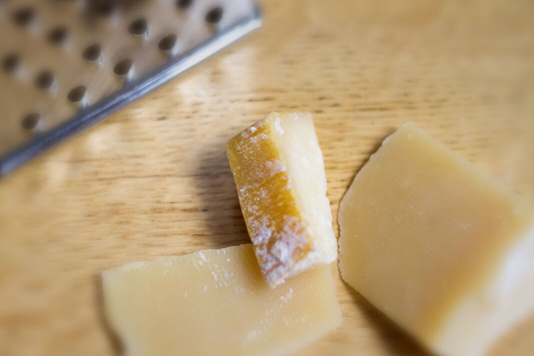 Écorces de parmesan, fond en bois, râpe à fromage