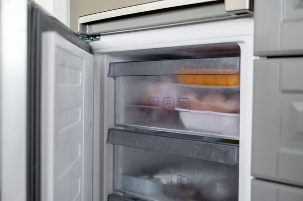 Porte du congélateur ouverte avec des tiroirs remplis d'aliments surgelés