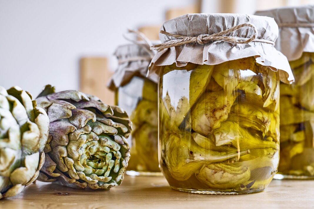 Artichauts fermentés conservés à l'huile d'olive dans des bocaux en verre sur une table en bois. Conserve de légumes d'automne. Nourriture saine faite maison. Artichauts fermentés conservés à l'huile d'olive dans des bocaux en verre sur une table en bois. Conserve de légumes d'automne. Nourriture saine faite maison.