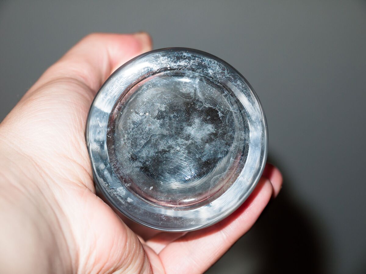 bouteille à fond de verre tenue en main jusqu'aux légères taches et poussières