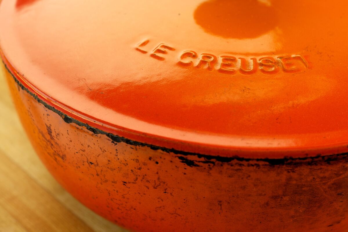 Marmite orange Le Creuset en fonte avec marques de brûlure et de détresse