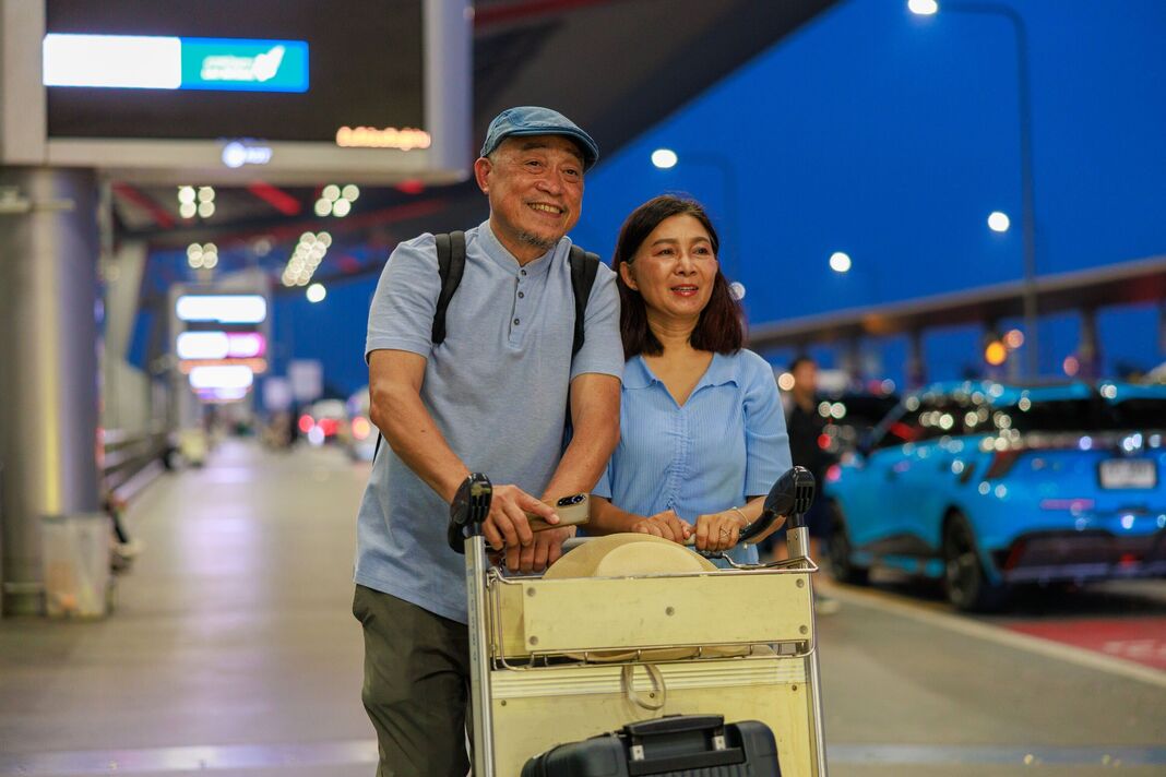 Couple de personnes âgées asiatiques chargeant des bagages sur un chariot de l'aéroport