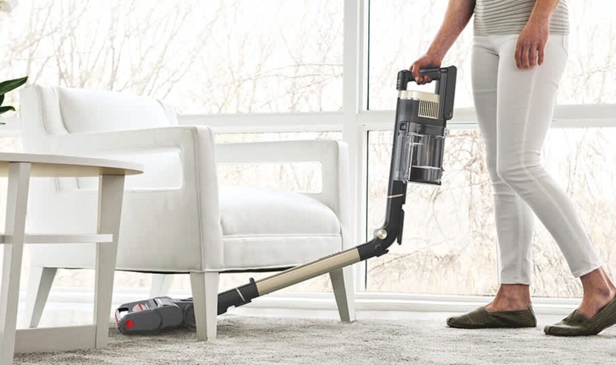 Femme passant l'aspirateur sous une chaise