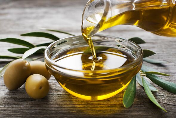 Bouteille versant de l'huile d'olive vierge dans un bol en gros plan