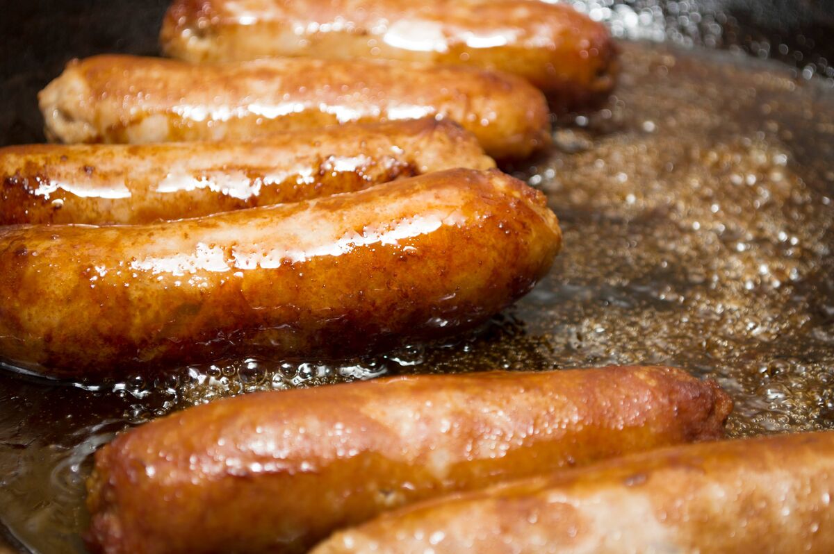 Saucisses frites appétissantes, en cours de cuisson. Cuire les saucisses. Nourriture pas saine