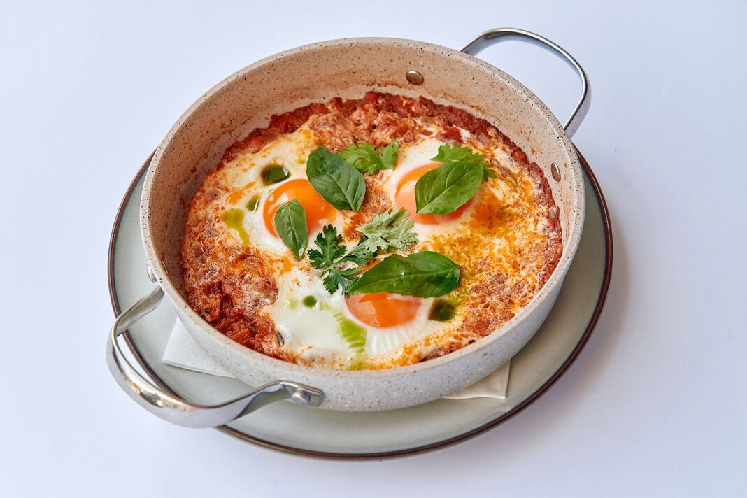 Shakshuka avec œufs pochés, herbes fraîches et riche sauce tomate dans un plat Le Creuset