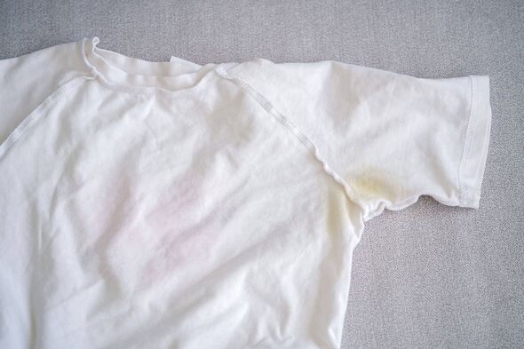 Une tache jaune sur un T-shirt blanc. Vue de dessus. Une tache jaune sur un T-shirt blanc. Vue de dessus.