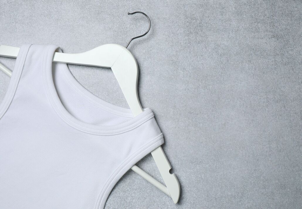 Cintre avec un T-shirt blanc sur fond gris. Maquette pour la conception Cintre avec un T-shirt blanc sur fond gris. Maquette pour la conception