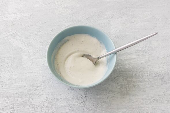 Bol bleu avec vinaigrette à base de crème sure, mayonnaise, vinaigre de vin et épices sur fond gris clair Bol bleu avec vinaigrette à base de crème sure, mayonnaise, vinaigre de vin et épices sur fond gris clair
