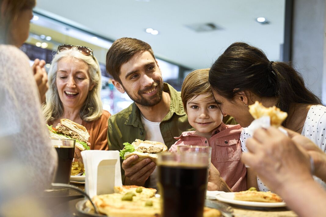 Famille s'amusant pendant l'heure du déjeuner dans l'aire de restauration du centre commercial