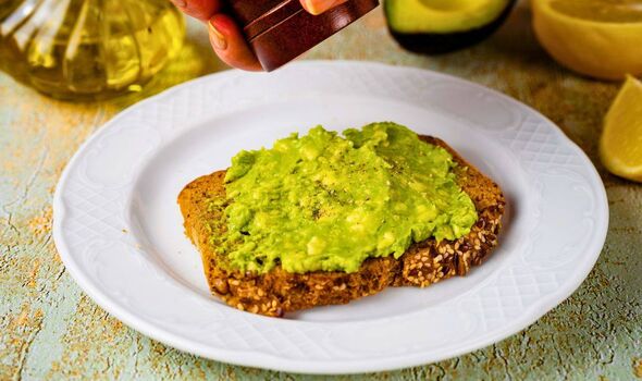Photo de quelqu'un assaisonnant un avocat et du pain grillé