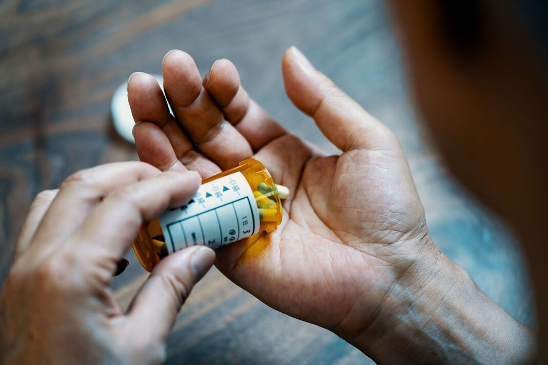 Gros plan d'une main masculine tenant une bouteille de pilules Gros plan d'une main masculine tenant une bouteille de pilules