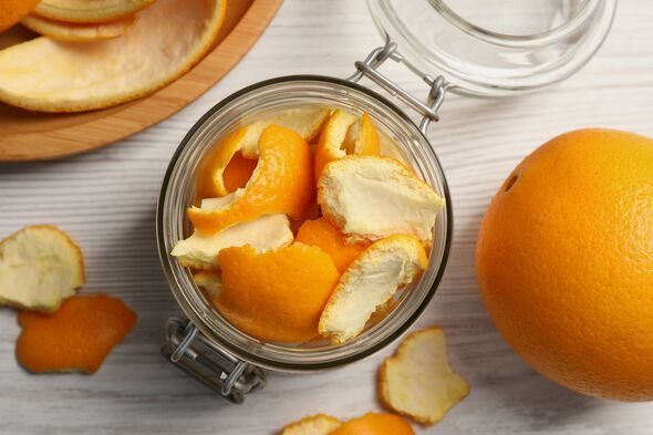Pelures d'orange se préparant au séchage et fruits frais sur une table en bois blanc, à plat