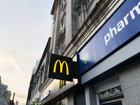 Manchester, Royaume-Uni - 29 septembre 2025 : les vitrines urbaines de Manchester comportent une enseigne McDonald's et une enseigne bleue de pharmacie le long d'un qui