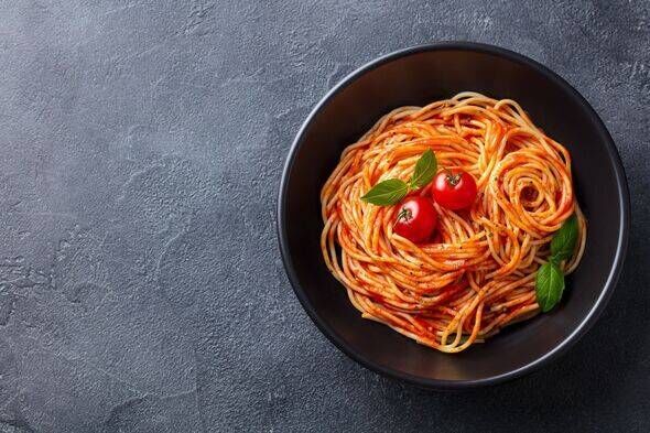 Pâtes, spaghettis à la sauce tomate dans un bol noir Pâtes, spaghettis à la sauce tomate dans un bol noir