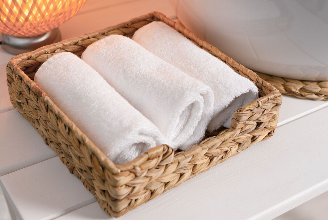 Trois serviettes blanches en gros plan, empilées dans un panier en osier de bambou Trois serviettes blanches en gros plan, empilées dans un panier en osier de bambou
