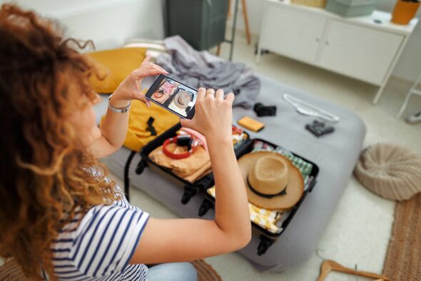 Individu assis à une table, en train de capturer des images ou des vidéos avec un appareil mobile. Divers objets personnels un Individu assis à une table, en train de capturer des images ou des vidéos avec un appareil mobile. Divers objets personnels un