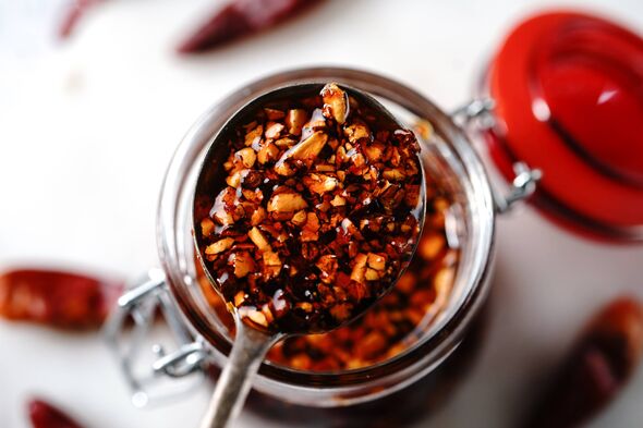 Huile de piment asiatique maison dans un bocal en verre, mise au point sélective Huile de piment asiatique maison dans un bocal en verre, mise au point sélective