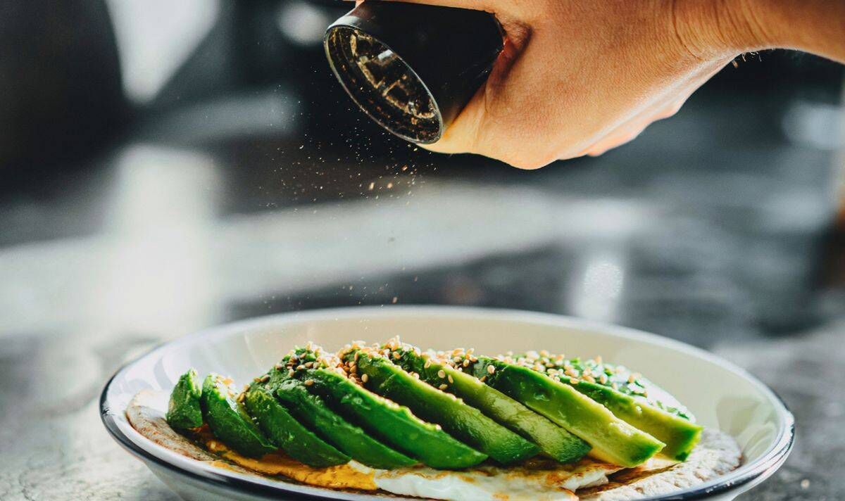 Photo de quelqu'un assaisonnant un avocat sur du pain grillé Photo de quelqu'un assaisonnant un avocat sur du pain grillé