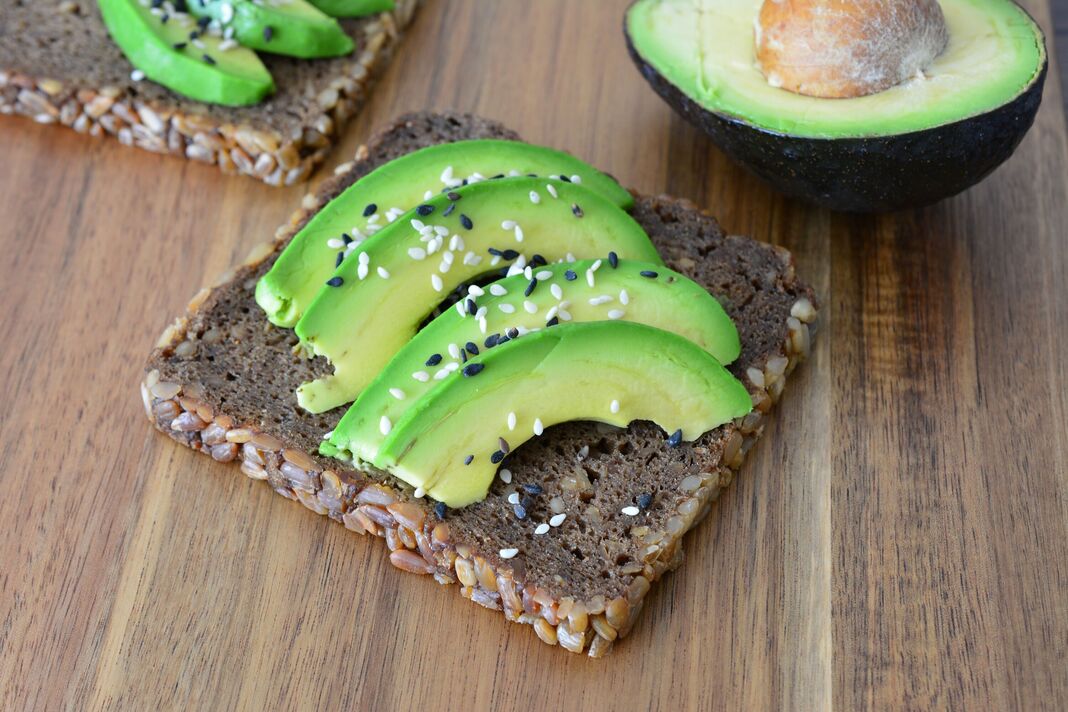 Toast à l'avocat avec tranches d'avocat et graines de sésame sur planche de bois Toast à l'avocat avec tranches d'avocat et graines de sésame sur planche de bois