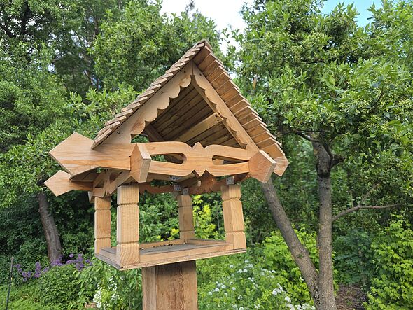 Mangeoire à oiseaux en bois dans un jardin luxuriant Mangeoire à oiseaux en bois dans un jardin luxuriant